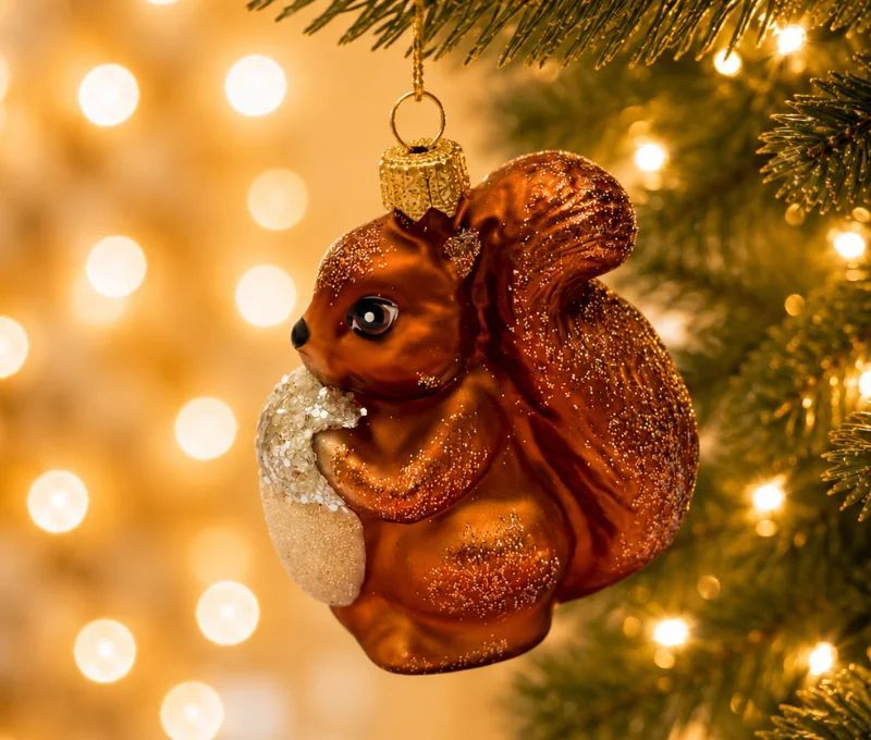 Suspension de Noël en verre soufflé en forme d'écureuil roux pailleté tenant un gland blanc givré H 7 cm sur fond blanc