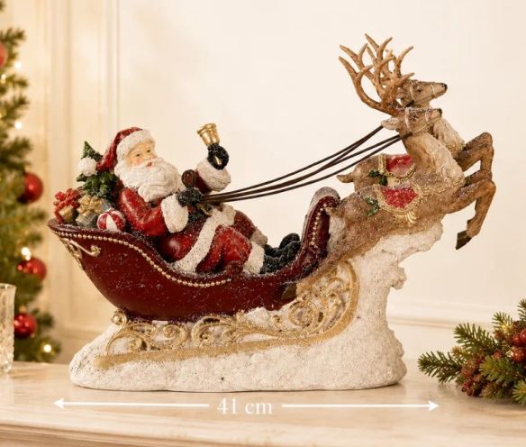 Décoration de Noël Père Noël traîneau rouge doré deux rennes cadeaux socle neigeux L42xl14xH36cm