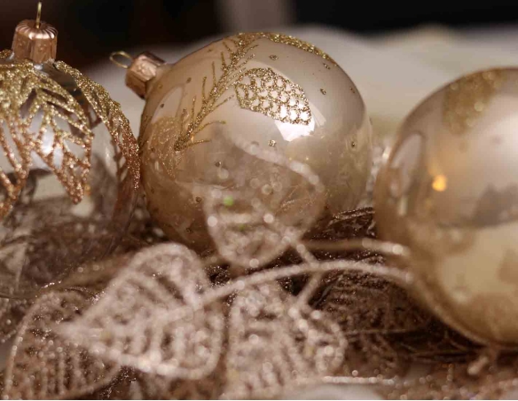 Boule de Noël en verre soufflé couleur champagne brillante avec décor pommes de pin en paillettes dorées. Diamètre 8cm.