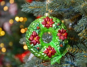 Suspension de Noël en verre soufflé en forme de couronne de Noël avec décors de poinsettia rouges. Diamètre 10cm