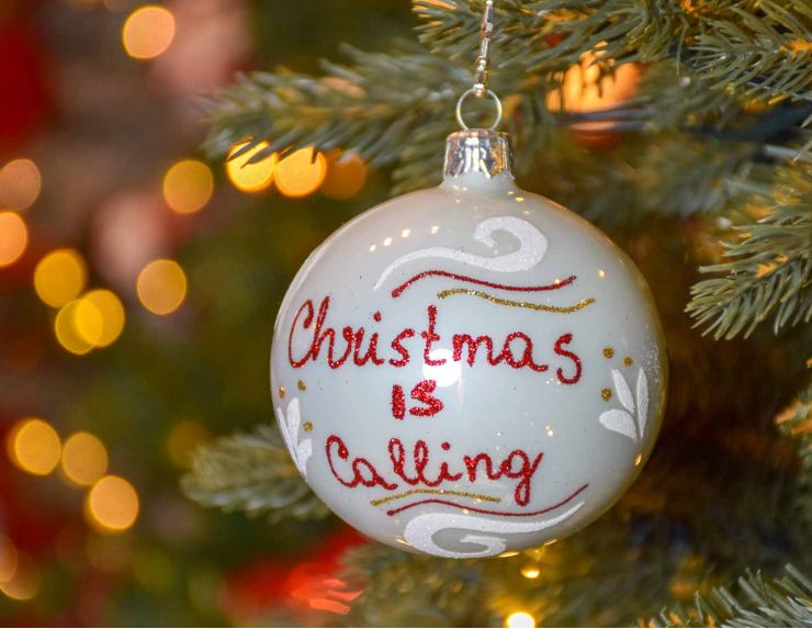 Boule de Noël blanche brillante avec inscription "Christmas is calling" en rouge pailleté,