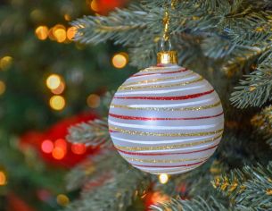 Boule de Noël blanche en verre recouverte de paillettes dorées, rouges et blanche en spirale tout autour de la boule.