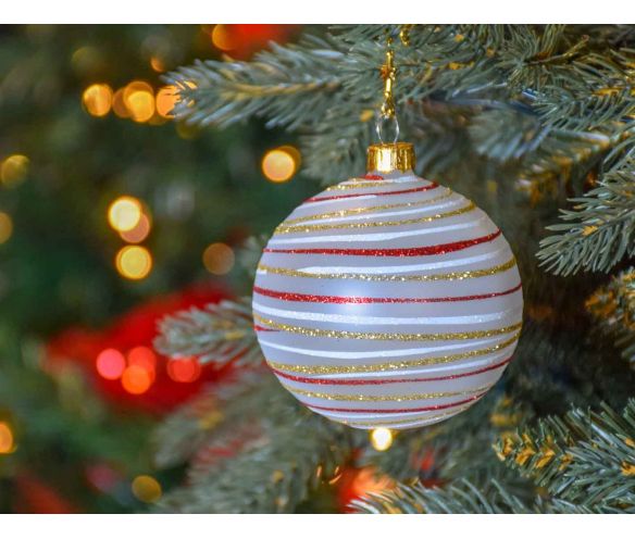 Boule de Noël blanche en verre recouverte de paillettes dorées, rouges et blanche en spirale tout autour de la boule.