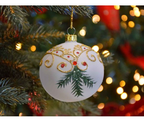 Boule de Noël blanche translucide avec décors de Noël traditionnel dorés et branches vertes.