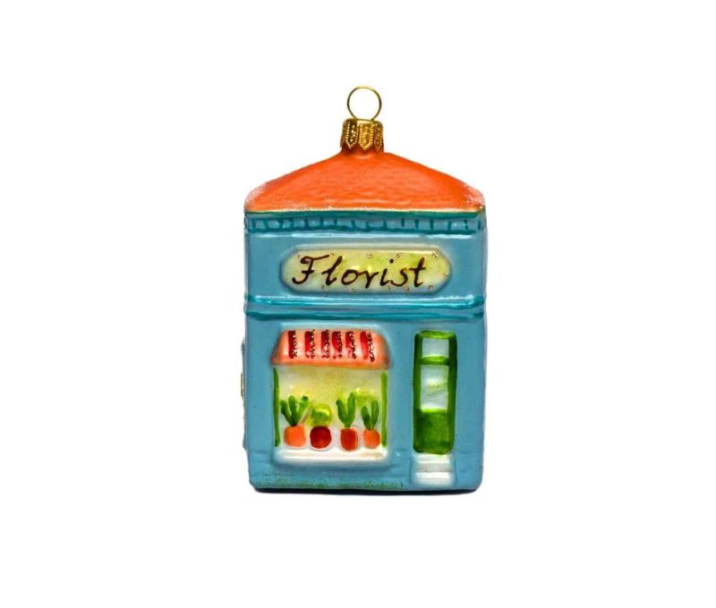 Suspension en forme de boutique de fleuriste, toit orange, façade bleue et vitrine fleurie. Verre soufflé, hauteur 10 cm.