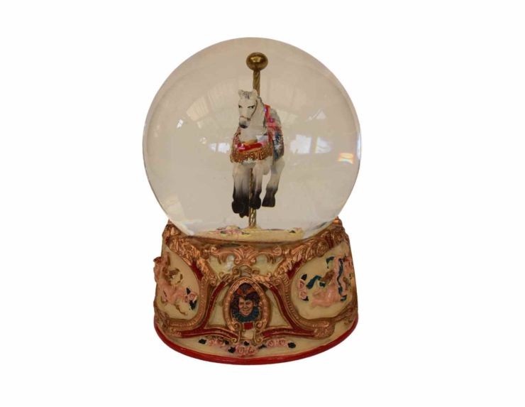 Boule à neige en verre et résine, hauteur 14 cm, cheval de carrousel détaillé sur socle orné de motifs baroques.